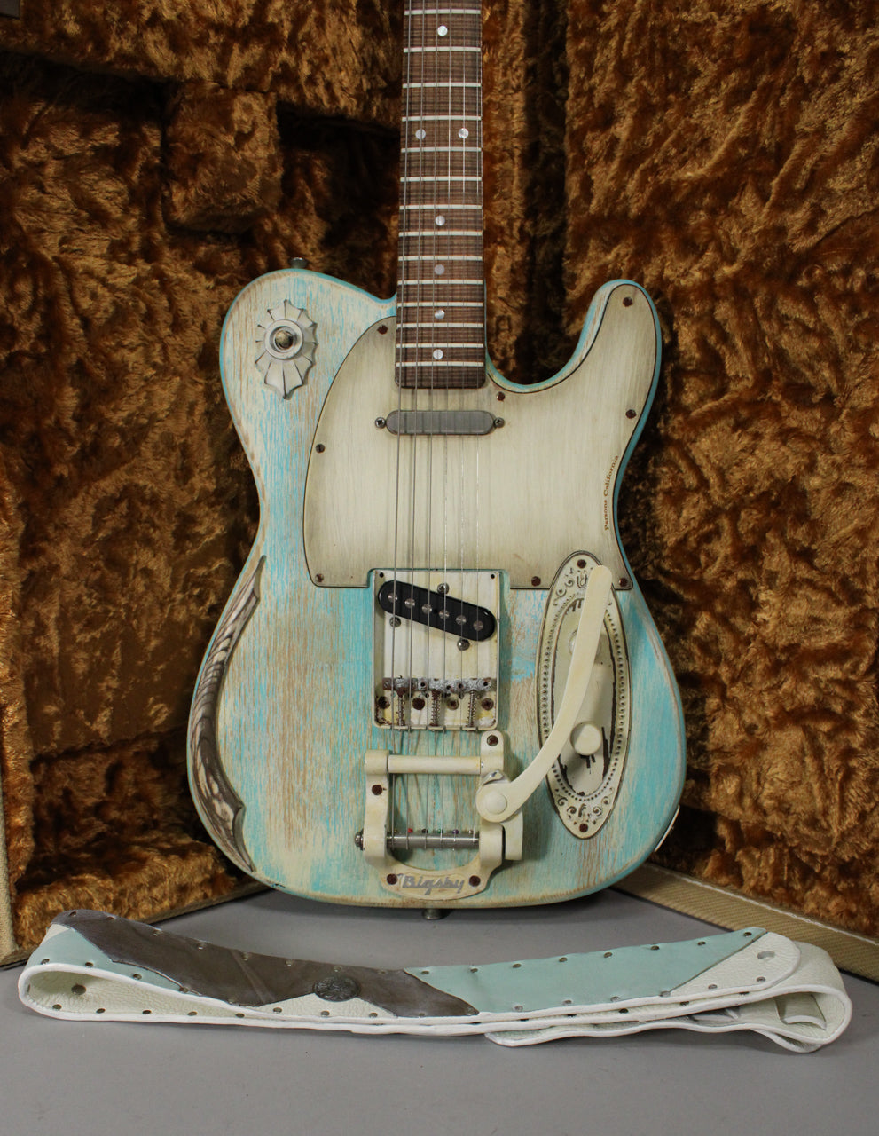 Full view of a heavily relic'd blue and cream electric guitar with a Bigsby tremolo, a single coil bridge pickup, and a matching strap.