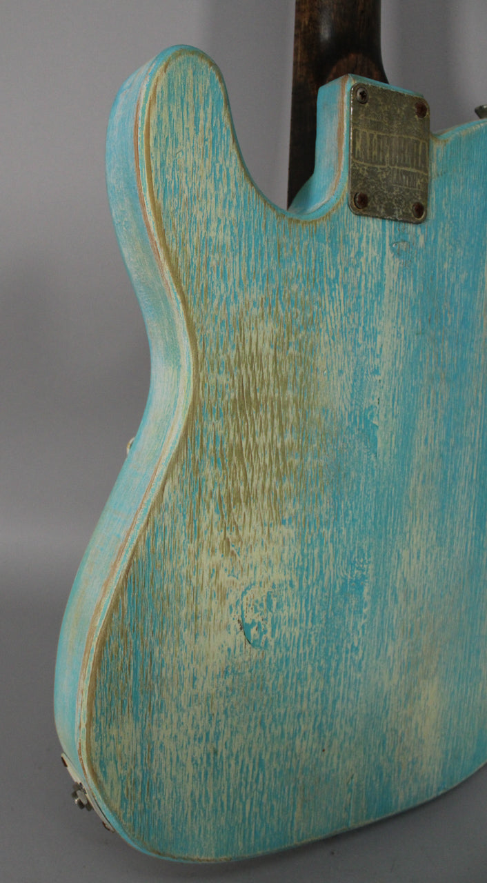 The guitar's back, angled left, shows a heavily relic'd blue finish with exposed wood grain and a worn metal neck plate.