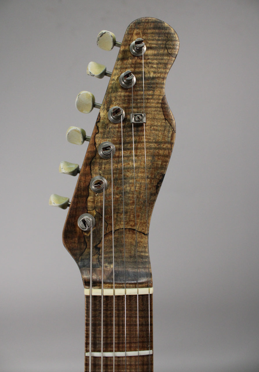 Close-up of the guitar's headstock and top of the fretboard, showing heavily relic'd wood grain, six worn tuning pegs, and string tree.