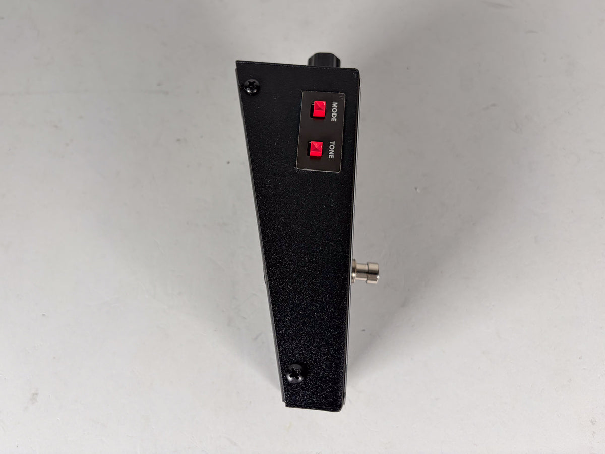 The black pedal is viewed from the side, showing two red rectangular buttons labeled "MODE" and "TONE".