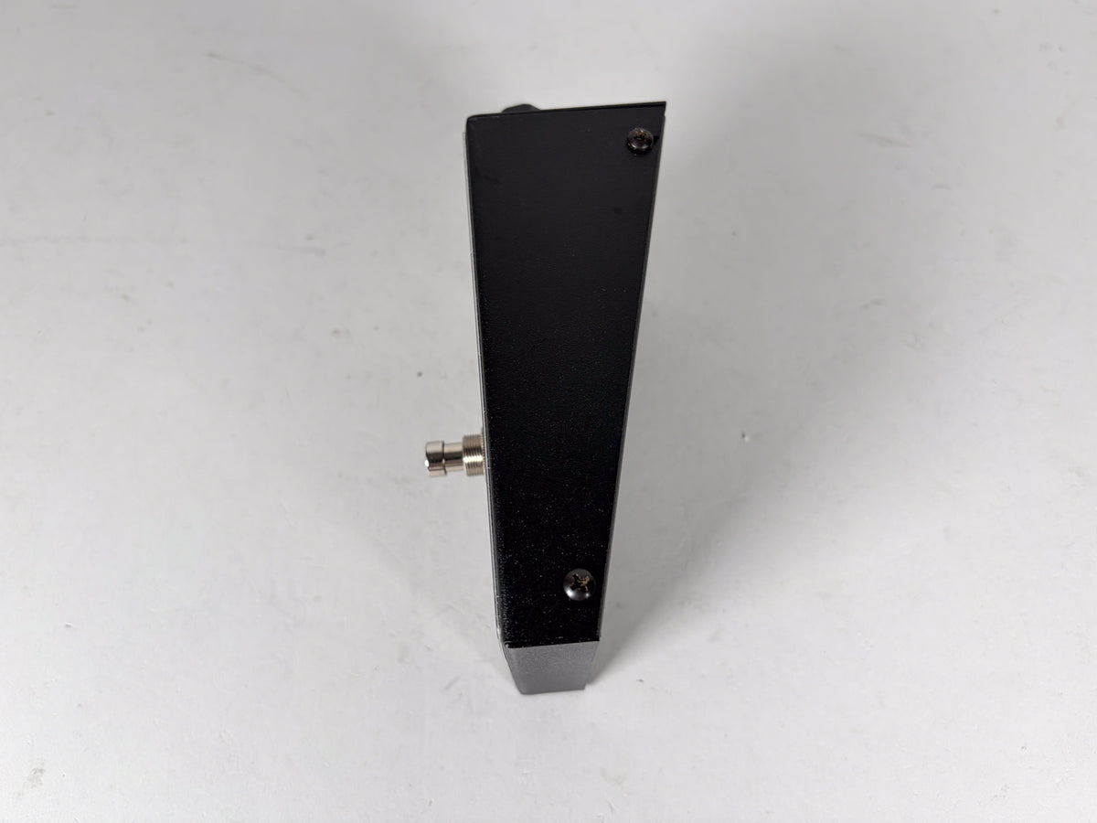 The black, textured metal pedal is viewed from its right side, showing a silver input jack and two visible screws.