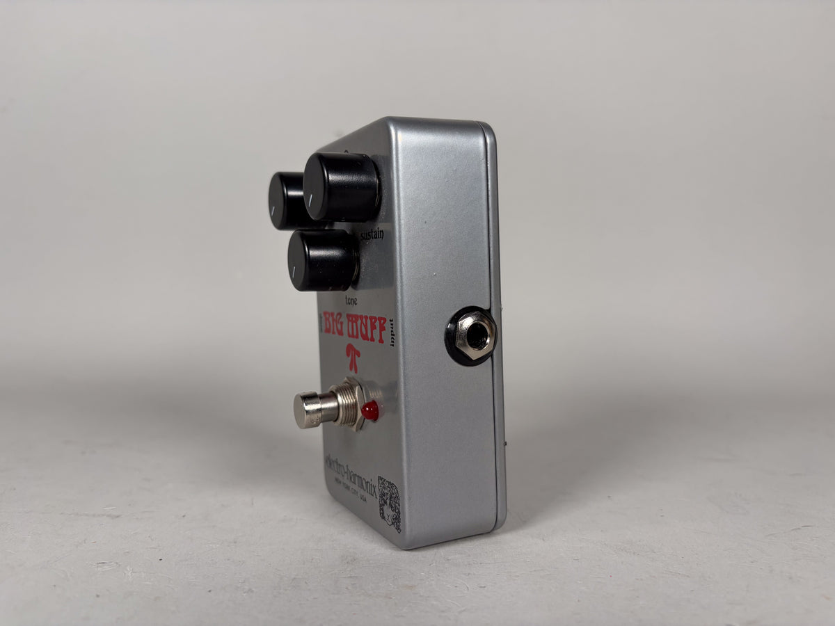 Silver guitar pedal shown from the right side, with three black control knobs, a chrome footswitch, a red LED, and an input jack.
