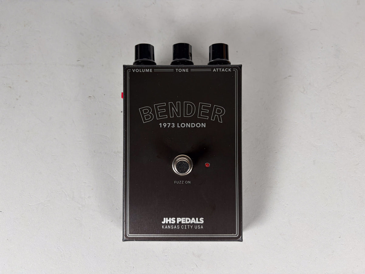 Top-down view of a rectangular black fuzz pedal with three black knobs, a silver footswitch, and a small red LED.