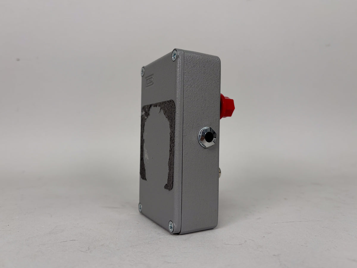 The gray pedal is viewed from the right side, showing a red knob, a chrome jack, and a large area of worn-off finish.