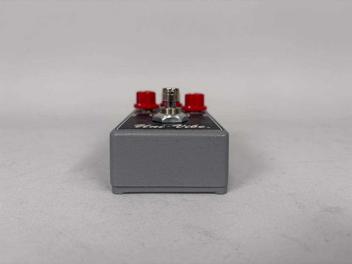 A gray MXR M68 Uni-Vibe pedal, viewed from the side, shows a black top panel with "Uni-Vibe" and three red knobs.
