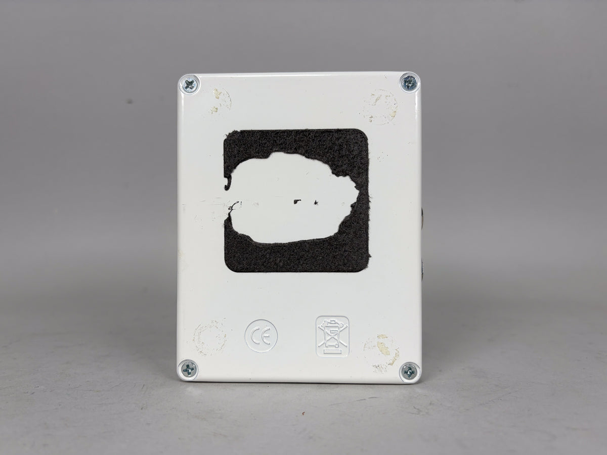 The white pedal's underside is shown, with a large, irregular patch of black hook-and-loop tape and four silver screws.