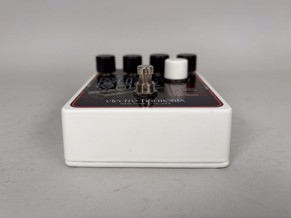A white guitar pedal, viewed from the right side, showing four black knobs and one white knob, with a silver footswitch.