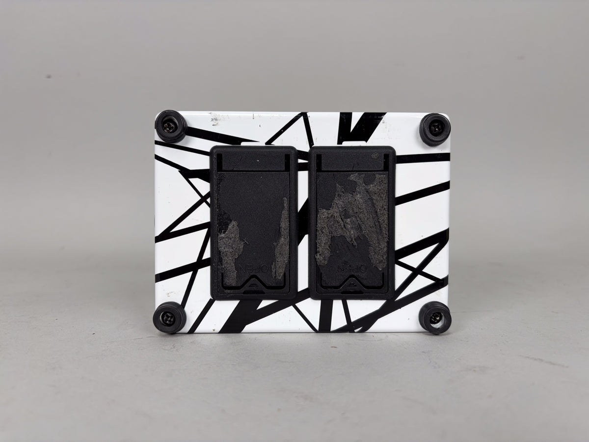 The pedal's top is white with black stripes, featuring two black footswitches with visible wear, and four black corner screws.