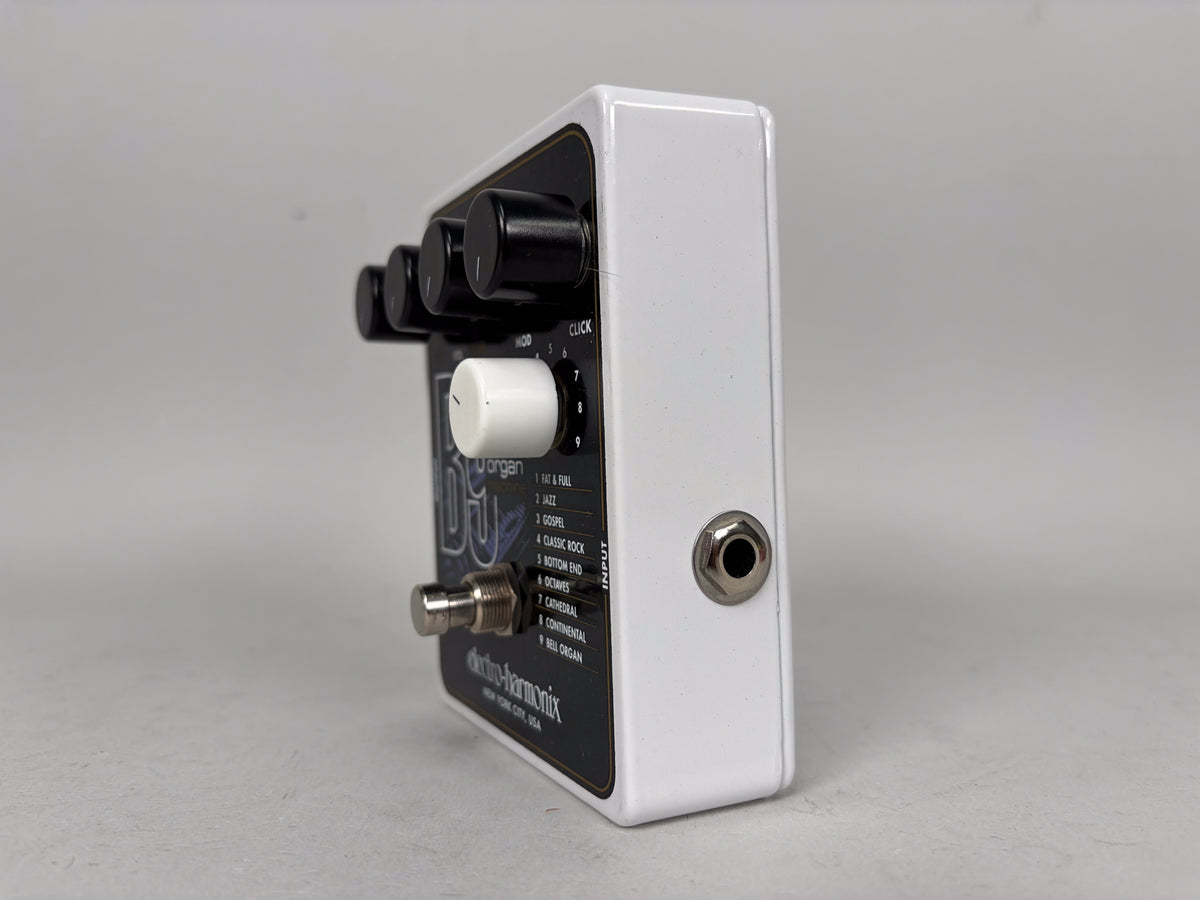 The white pedal is angled to show its right side with an input jack and part of the black control panel with four knobs.