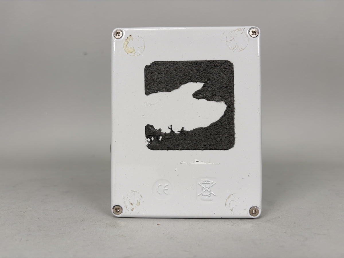 The white pedal's underside is visible, showing a large, irregular patch of worn black adhesive and four silver screws in the corners.
