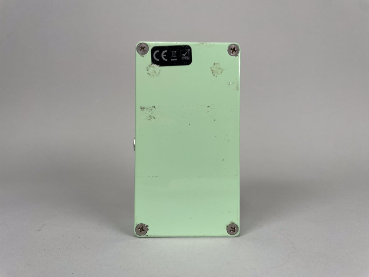 The mint green effect pedal is shown from the back, revealing a black CE sticker and four silver Phillips head screws.