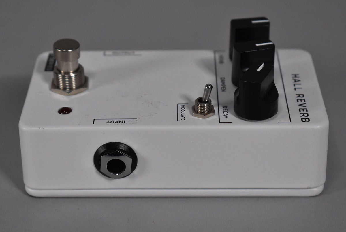 White pedal, angled from the front right, showing the input jack, footswitch, toggle switch, and two black control knobs.