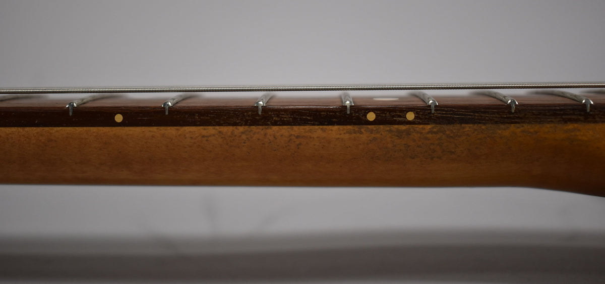 Close-up of the guitar's dark fretboard with gold dot inlays, showing light wear on the frets and a worn, amber-toned neck.