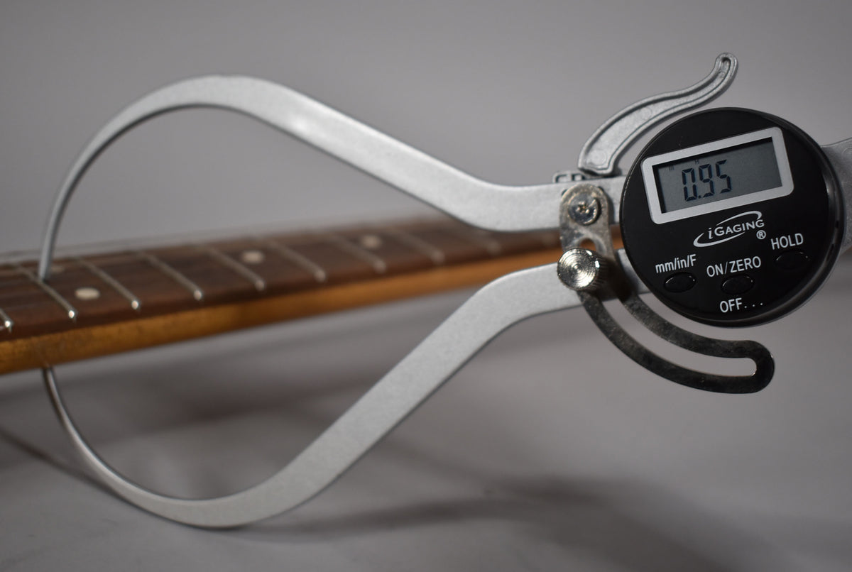 A digital caliper measures the fret height at 0.95mm on the guitar's rosewood fretboard with dot inlays.