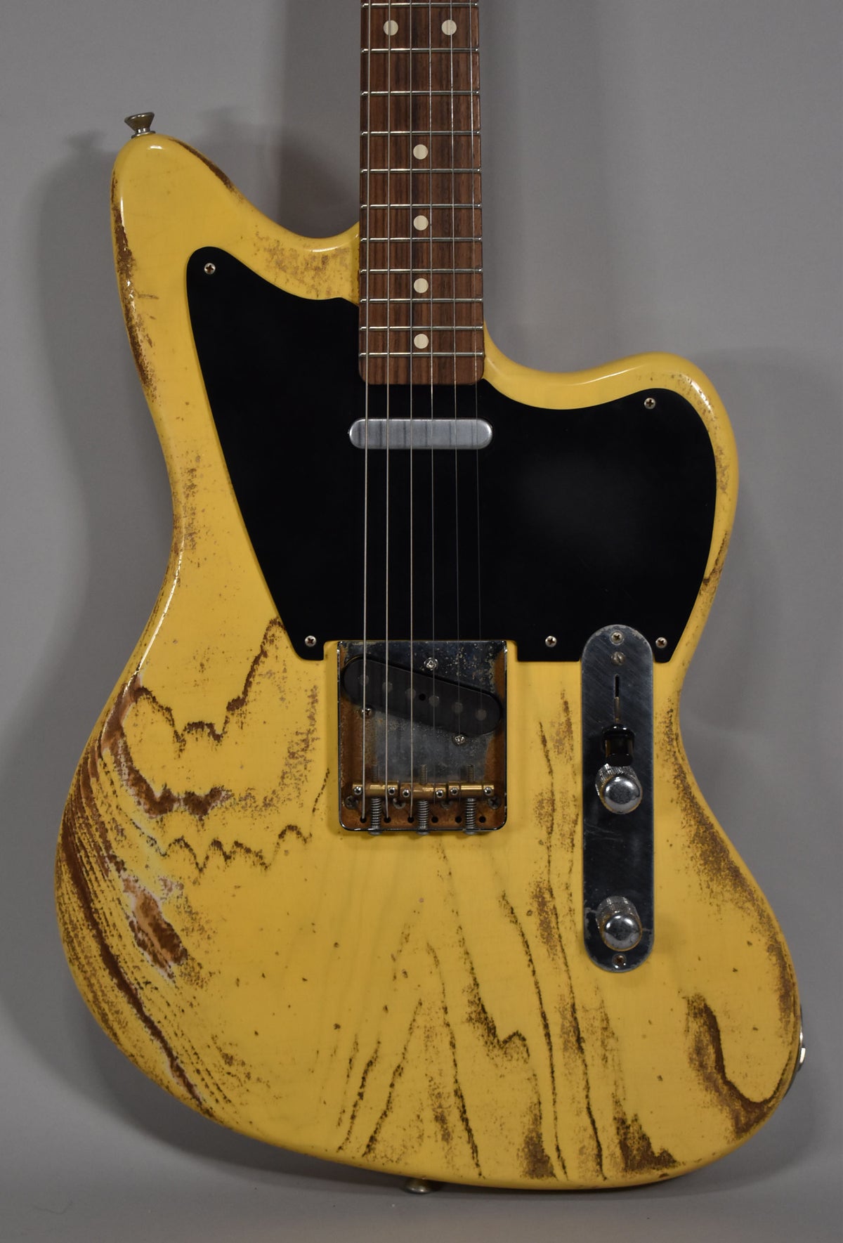 Full-frame view of the distressed butterscotch blonde guitar, showing a black pickguard, single-coil neck pickup, and a Tele-style bridge.
