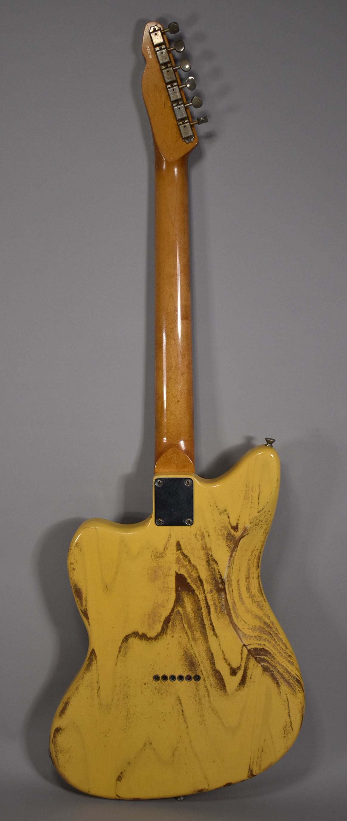 The back of a butterscotch blonde guitar with a heavily relic'd finish, showing dark brown wear patterns and a shiny maple neck.