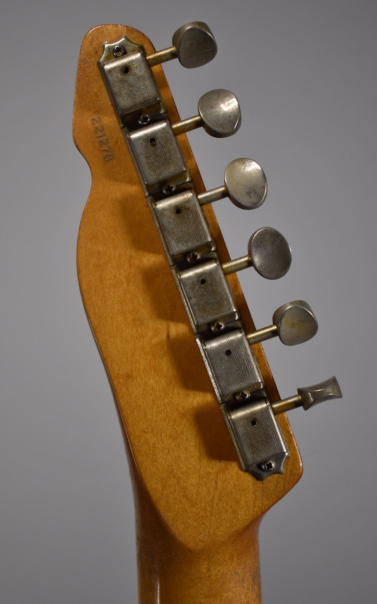The guitar's headstock and tuning machines are shown from the back, with a worn, butterscotch blonde finish and relic'd hardware.