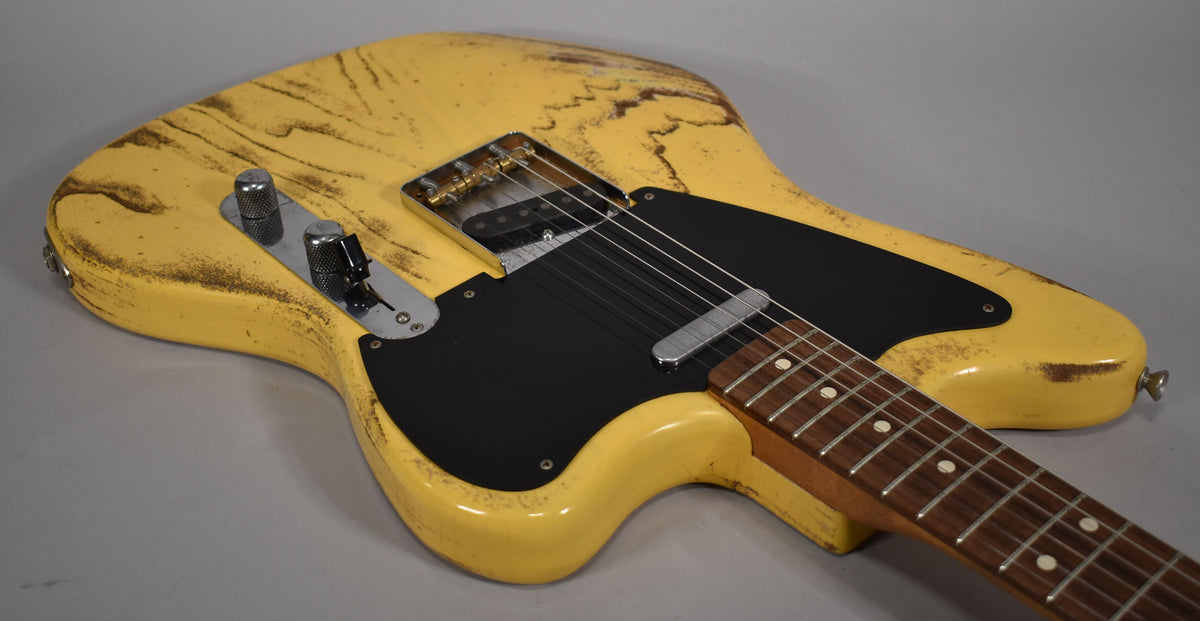 The butterscotch blonde guitar body, with heavy relic wear and a black pickguard, is angled from the upper left.