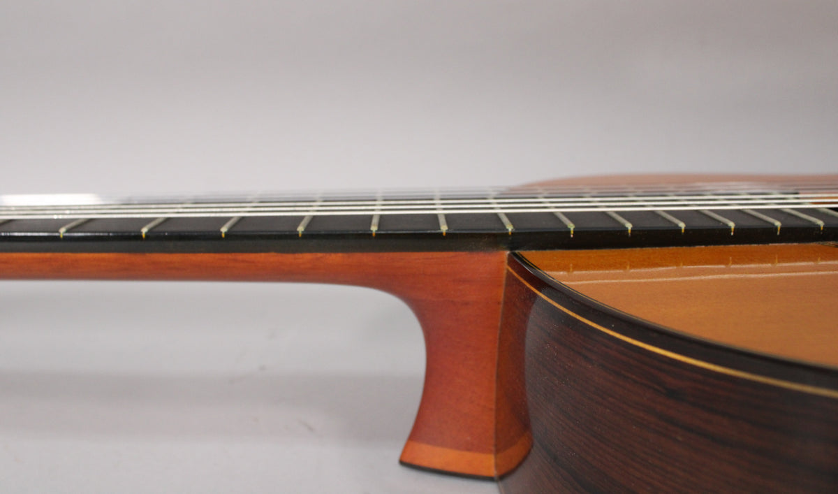 Close-up of the guitar's neck joint and lower bout, showing the dark fretboard, light brown neck, and dark wood body with binding.
