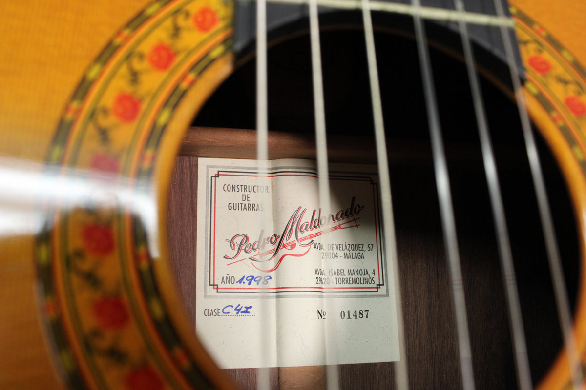 Close-up of the guitar's soundhole, revealing a white label with red and black text, and a decorative rosette with red flowers.