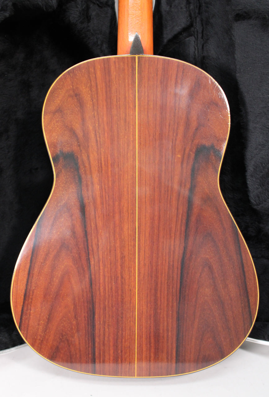 The guitar's back, a rich reddish-brown with dark grain and a light center stripe, shows some minor finish wear.
