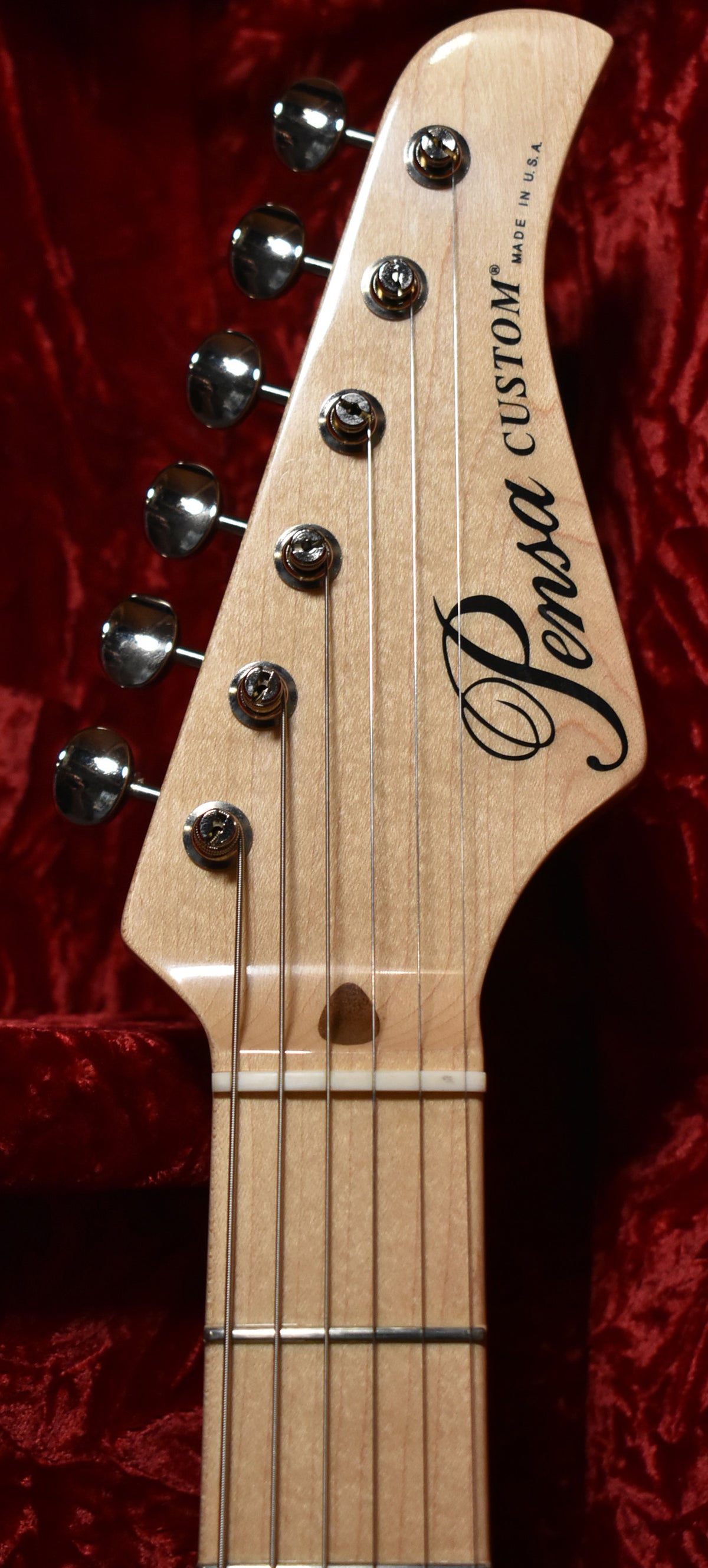Close-up of the light wood headstock and upper fretboard, showing six chrome tuners and a dark wood string tree.