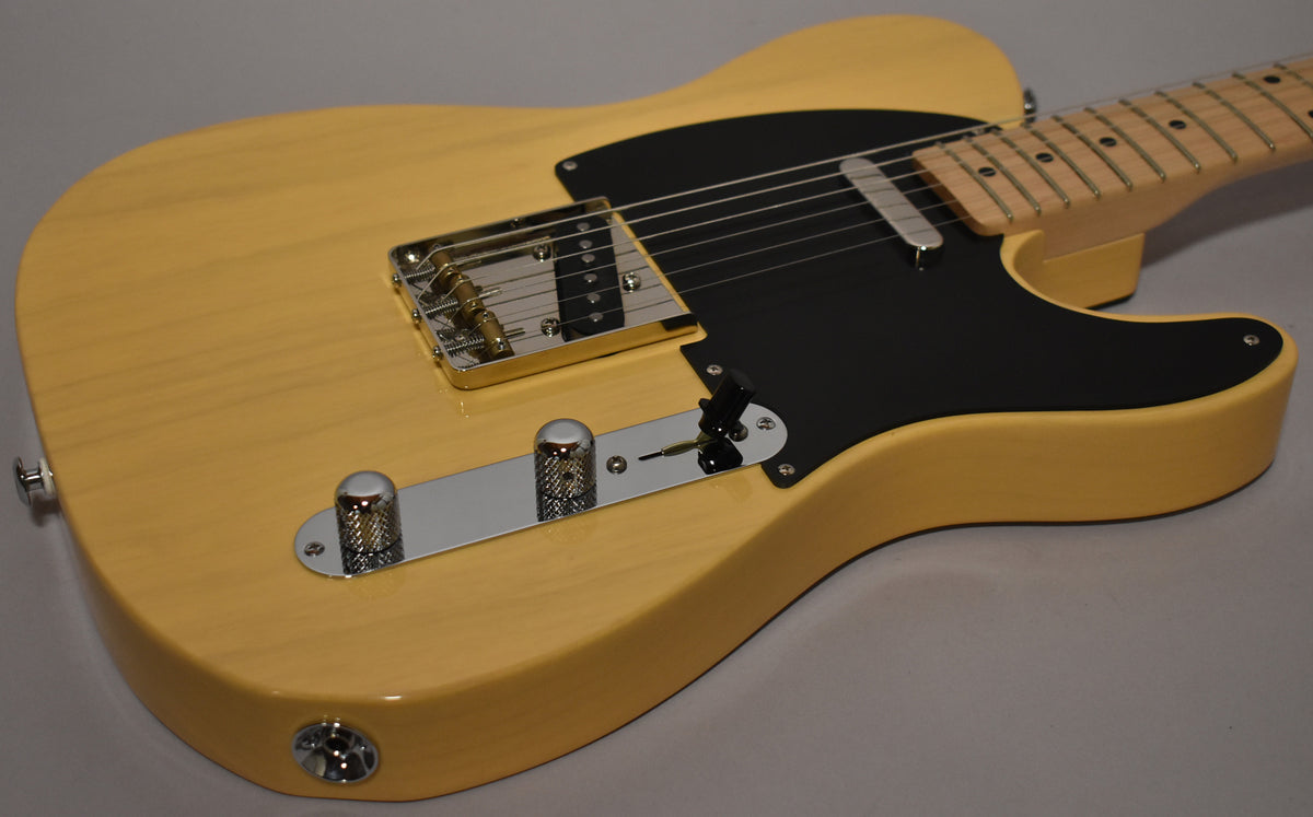 The butterscotch T-style guitar body, with a black pickguard and chrome hardware, is angled to show the bridge and control plate.
