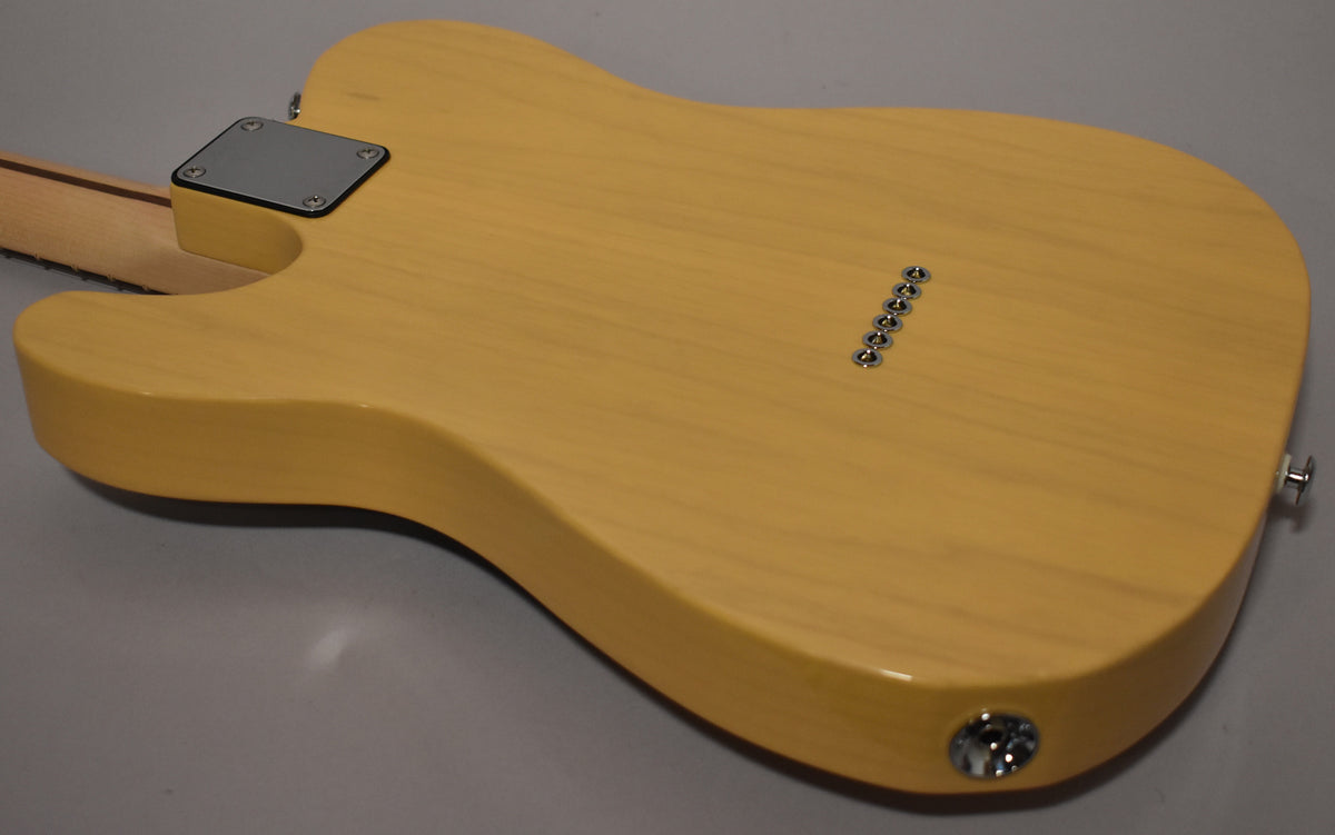 The butterscotch guitar's back shows a chrome neck plate, six string ferrules, and a side-mounted output jack.