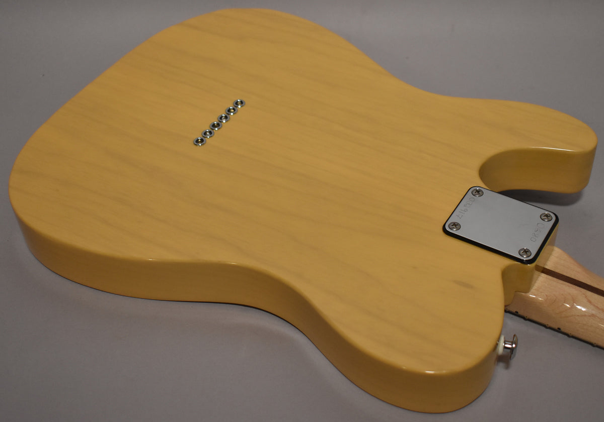 The butterscotch guitar's back shows a glossy finish, six string-through-body ferrules, a chrome neck plate, and a strap button.