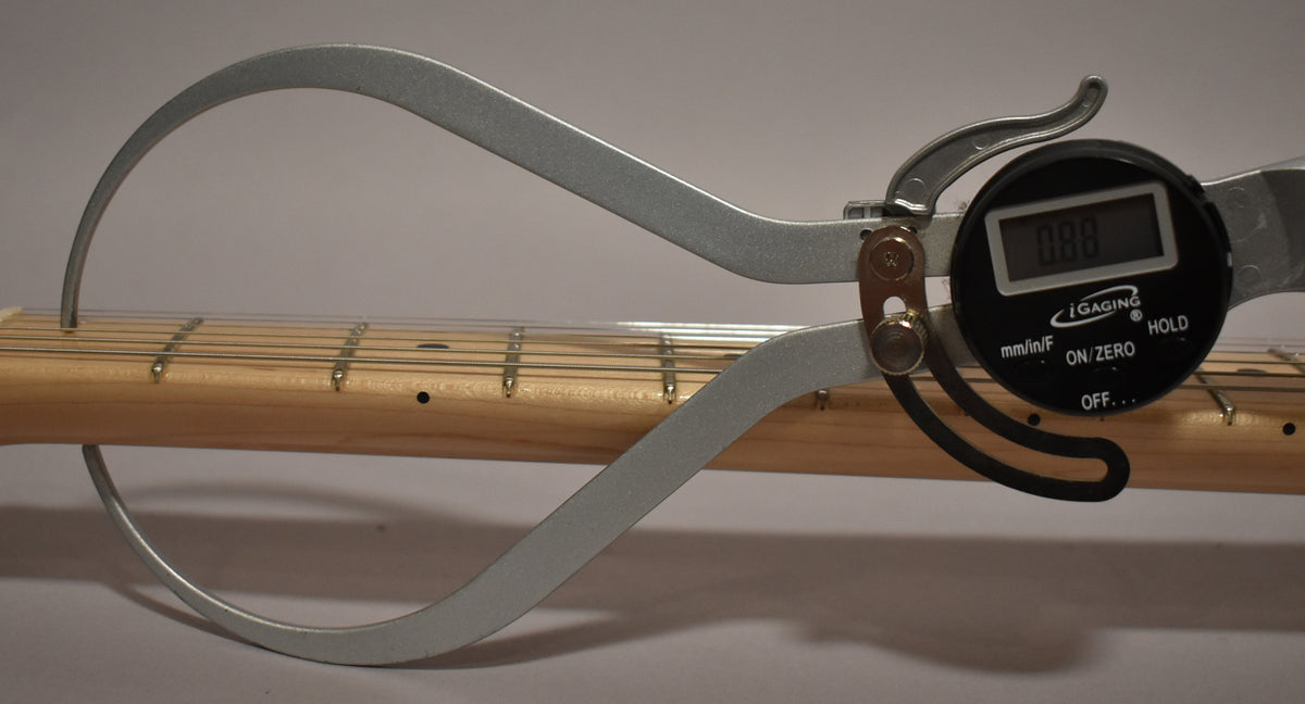 A digital caliper measures the light wood neck and fretboard, showing a reading of 0.88.