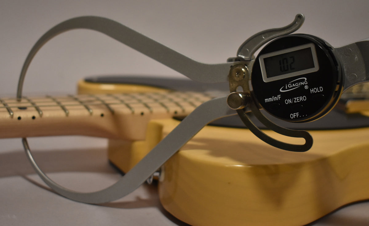 Close-up of the butterscotch body and light maple fretboard, with a digital caliper measuring the neck thickness at 1.02 inches.