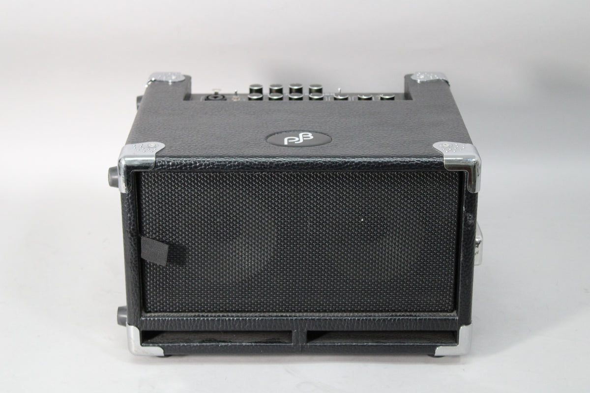 Front view of a black textured combo amp with a black speaker grille, chrome corner protectors, and top-mounted controls.