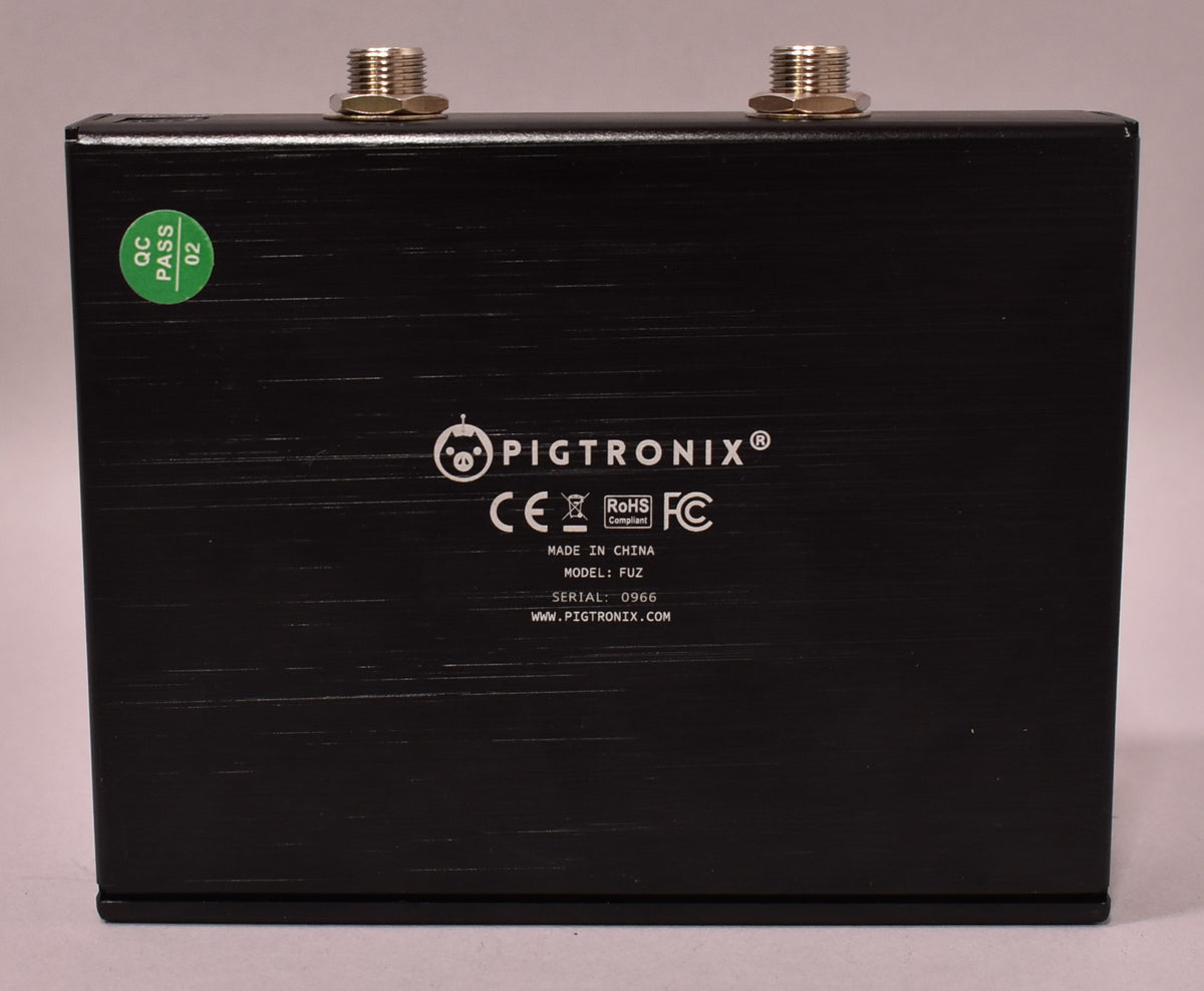 The pedal's black brushed metal back panel is visible, with two silver threaded posts and a green "QC PASS 02" sticker.