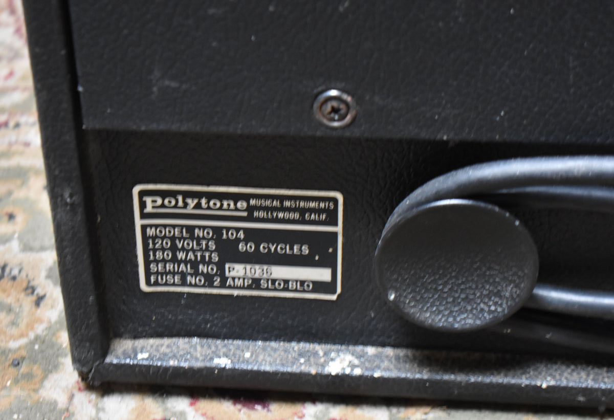 Close-up of the black textured rear panel, showing the white data plate with black text and a black power cord wrapped around a knob.