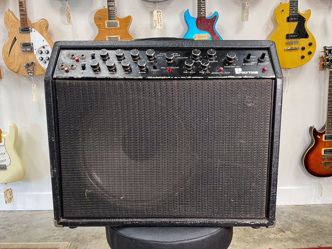 Front view of a black combo amp with a textured grille, a top control panel with numerous knobs and switches, and visible wear.