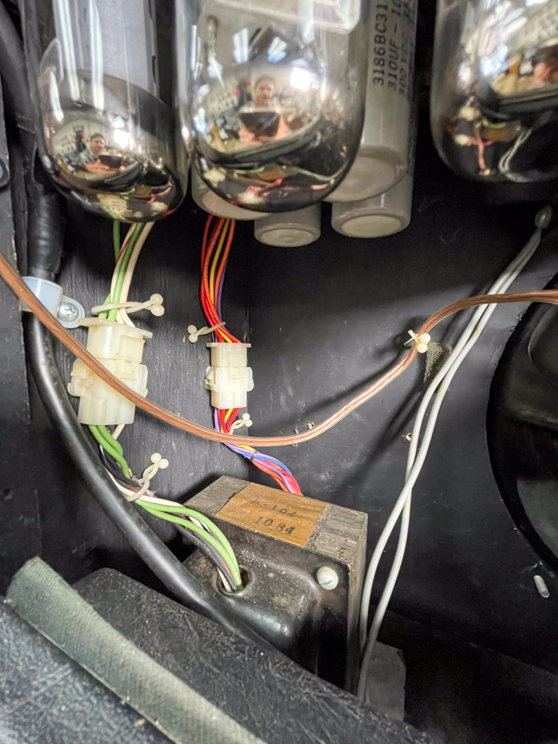 Close-up of the amp's internal wiring, showing several vacuum tubes, colorful wires, and a transformer with "10 84" visible.