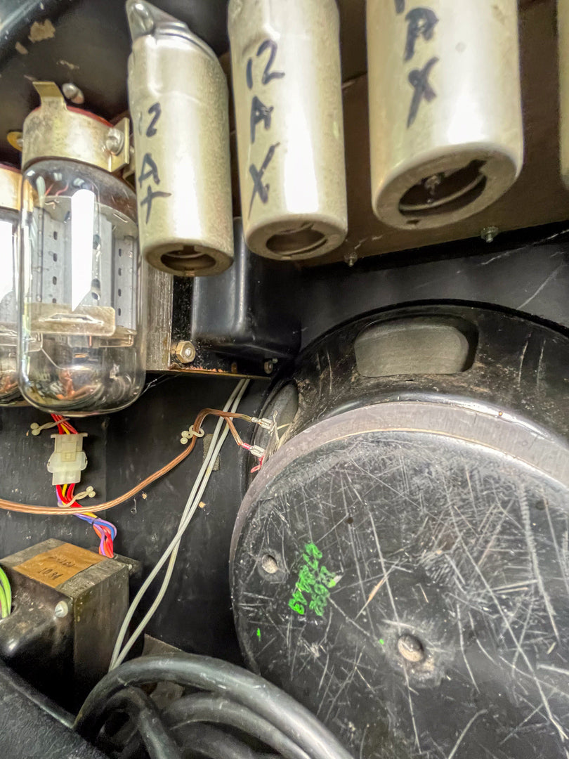 A close-up of the amp's interior shows three clear glass tubes, three metal-cased tubes, and a heavily scratched black speaker.