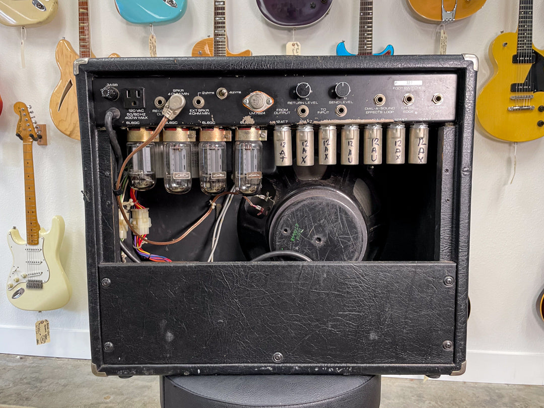 Rear view of the black combo amp, showing exposed tubes, a speaker, and various inputs/controls on the top panel.