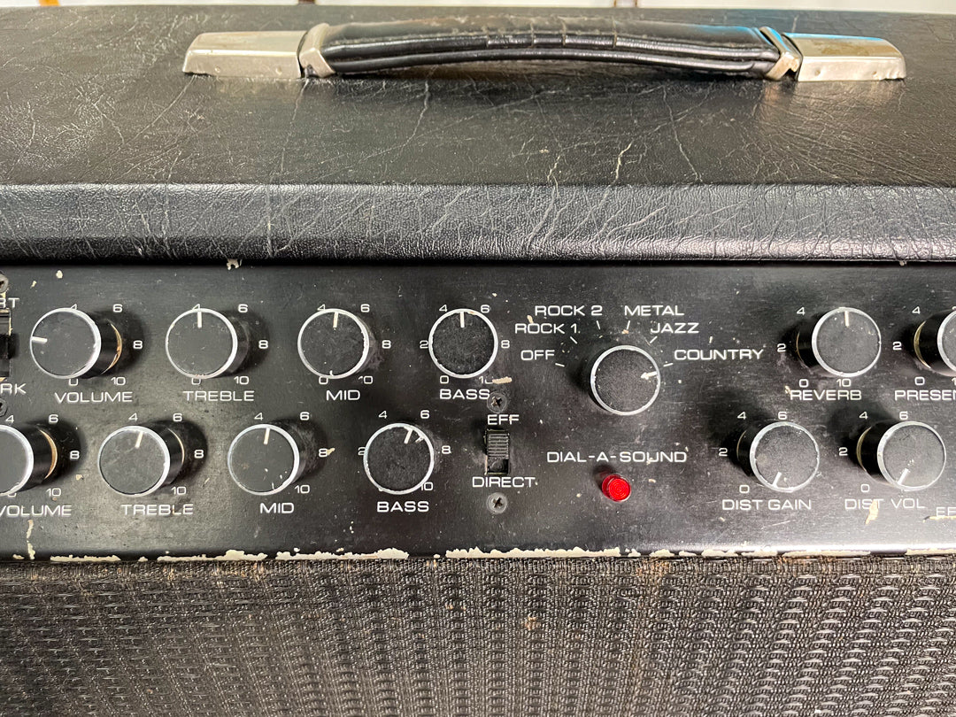 Close-up of the black amp's top control panel, showing numerous black knobs, a red indicator light, and worn white lettering.