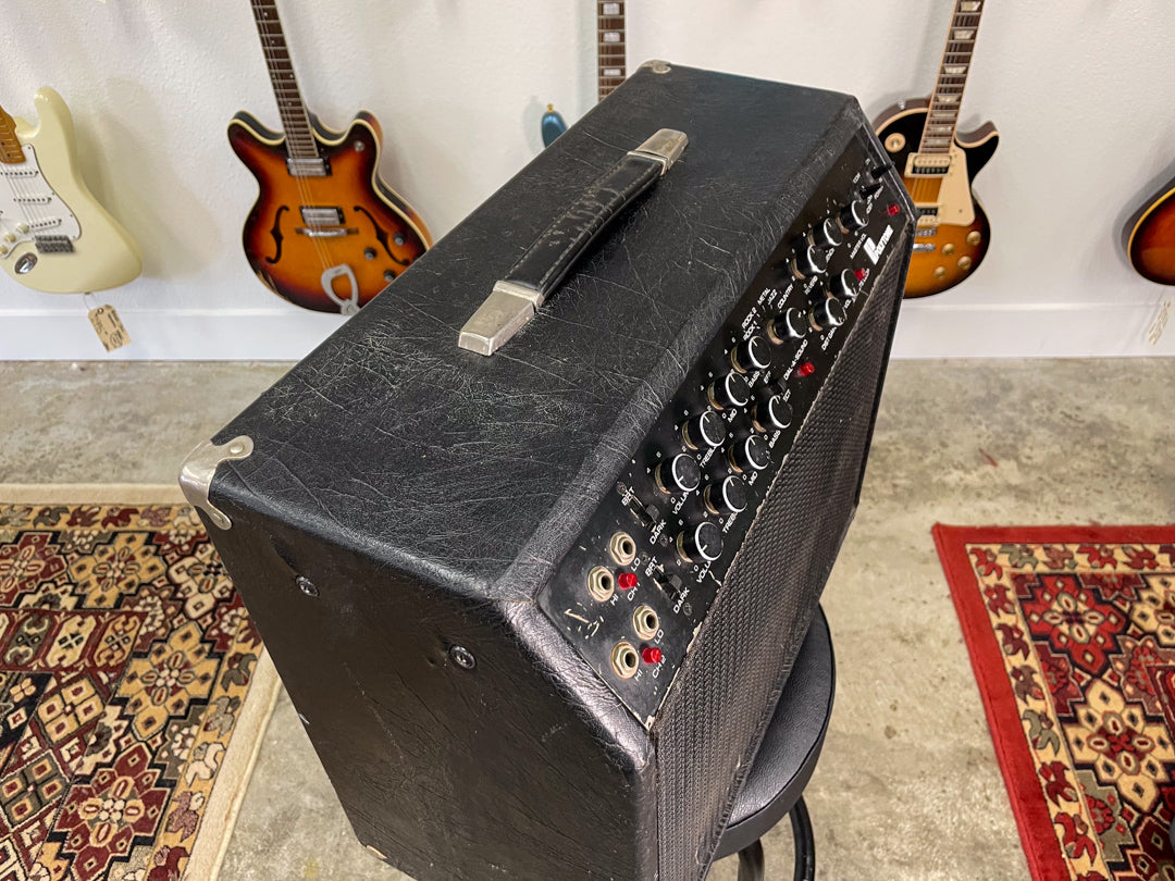 Black combo amp, angled from above, showing the worn top handle, metal corner protectors, and full control panel.