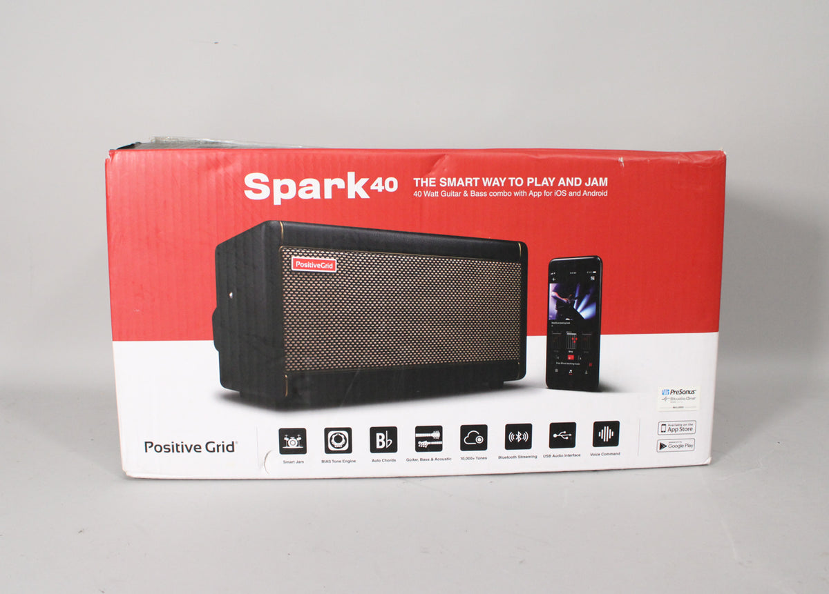 A red and white product box, slightly worn at the edges, displays a black amp with a gold grille and a smartphone.