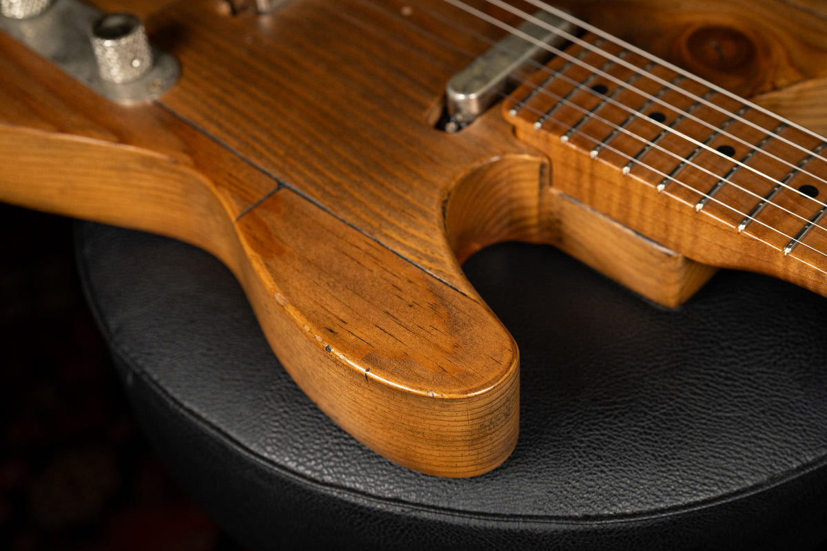 Close-up of the guitar's lower bout and neck joint, showing the natural wood grain, light relic wear, and a chrome neck pickup.