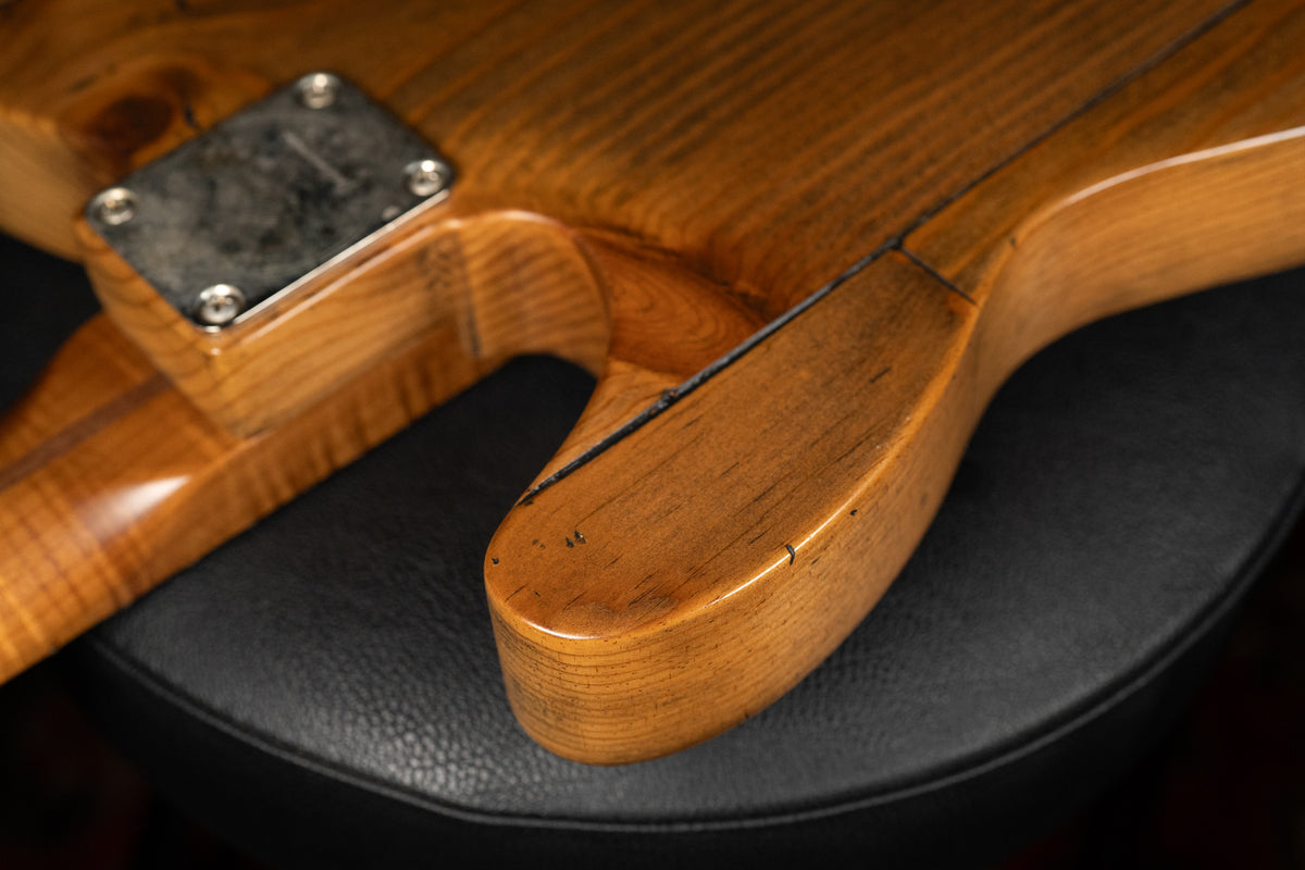 Close-up of the guitar's lower horn and neck joint from the back, showing a worn, light brown finish with visible wood grain and dark relicing.