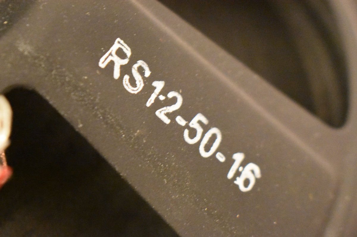 Close-up of the speaker's dark gray metal frame, showing white stenciled numbers and a hint of a white wire terminal.