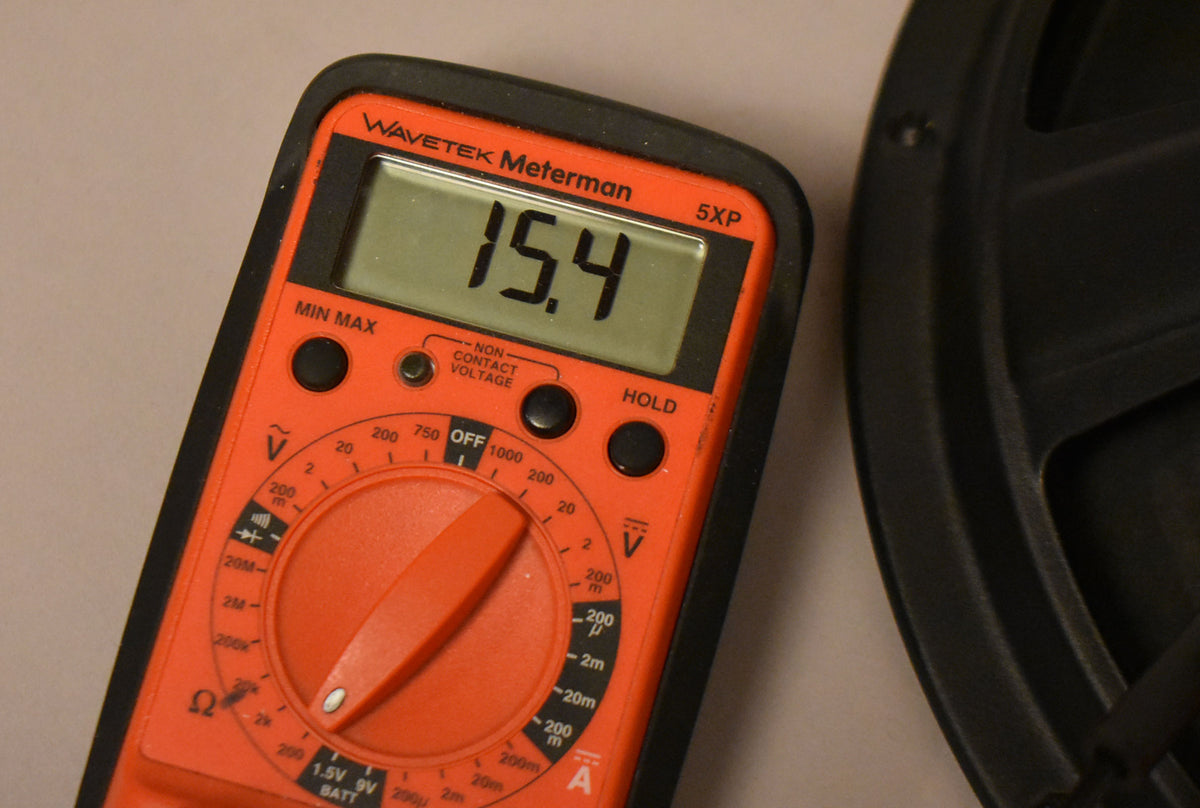 A red multimeter displays "15.4" next to the black speaker frame, showing its impedance.