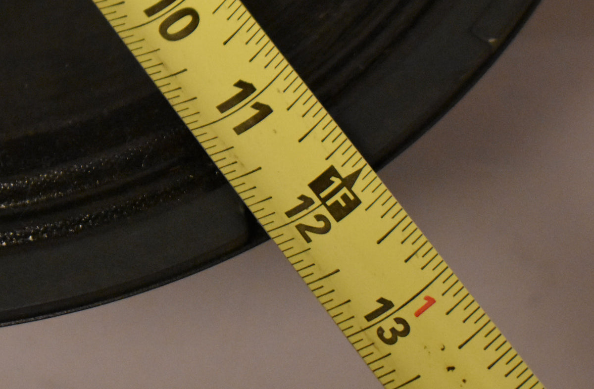 Close-up of the speaker's black cone and surround, with a yellow tape measure showing 10 to 13 inches across the diameter.