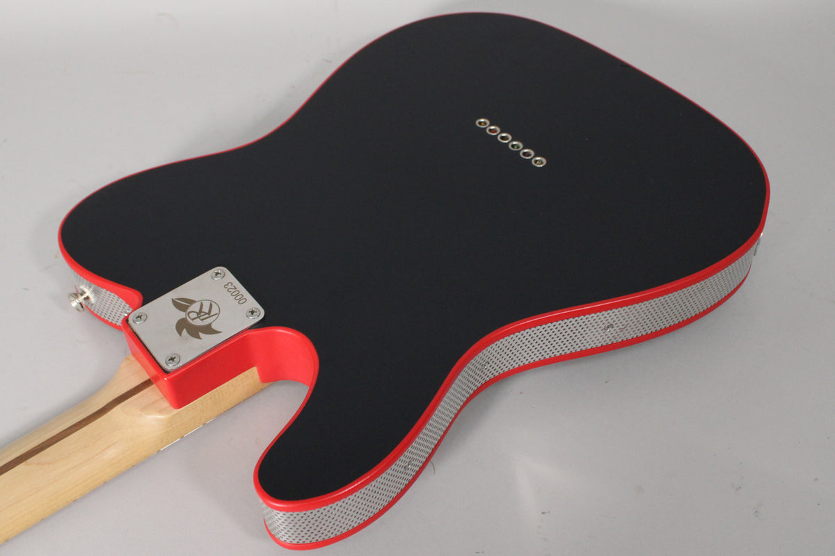 The guitar's matte black back and red sides with a silver perforated strip are visible, along with a light wood neck and string-through ferrules.