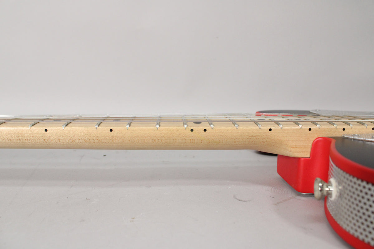 Side view of a guitar neck with a light wood finish and black dot inlays, attached to a red and black body with a chrome output jack.