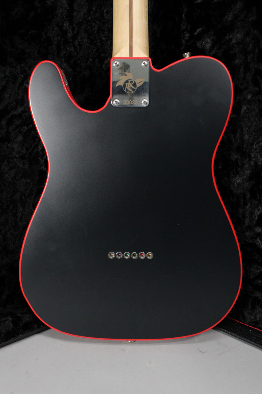 The guitar's matte black back with red binding is visible, showing a chrome neck plate and six string ferrules.