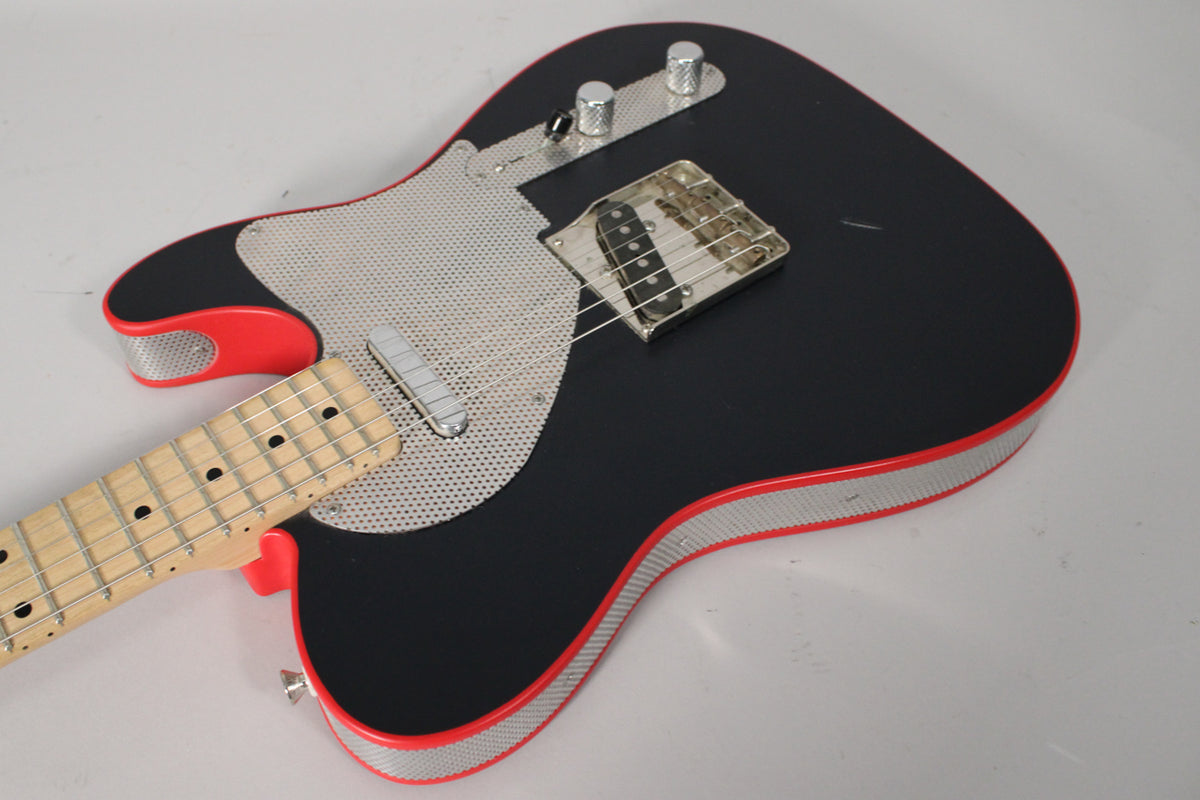 Matte black guitar body with red trim and a perforated metal pickguard, angled from the neck to the lower bout.